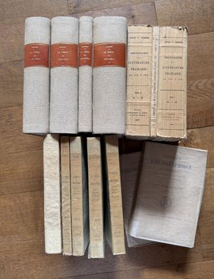 several books are stacked on top of each other on a wooden floor