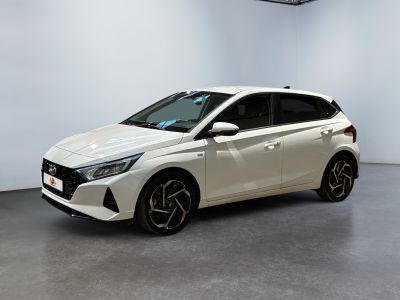 La voiture blanche est garée dans une grande pièce aux murs blancs.