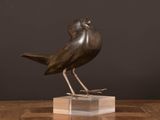 an image of a bronze bird sitting on top of a wooden table