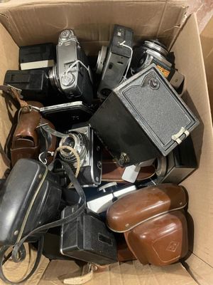 a cardboard box full of old cameras and other items
