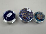 three glass magnets with different designs on them sitting on a table