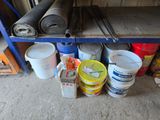 several buckets of paint are sitting on a shelf in a garage