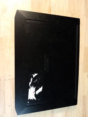 un ordinateur portable noir dont l'écran est cassé, posé sur une surface en bois