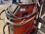 une photo d'une machine à souder dans une usine, avec de nombreux câbles
