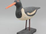 oiseau noir et blanc au bec orange, posé sur un socle noir