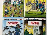 four books of french children ' s comics on a white surface