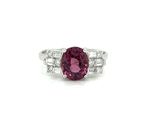 a close up of a ring with a pink stone surrounded by diamonds