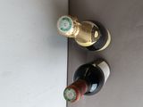 two bottles of wine sitting on a wall next to each other