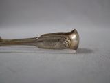 silver spoon with ornate design on it sitting on a white surface