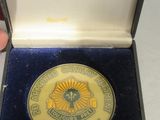 une médaille d'or dans un écrin noir posé sur une table blanche