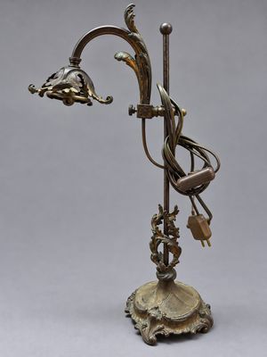 une lampe en bronze surmontée d'un oiseau, posée sur un socle