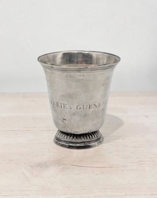 a silver cup on a wooden table with a white wall in the background