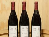 trois bouteilles de vin posées sur un tonneau