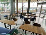 many tables and couches in a restaurant with a view of the water