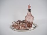 des bouteilles et des verres posés sur un plateau en argent, sur une surface blanche
