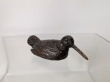 a small bronze bird sitting on a glass shelf