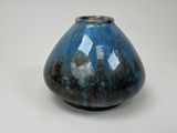 un vase bleu et noir posé sur une surface blanche