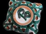 a close up of a ceramic object with a green and brown design