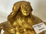 a gold statue of a woman with long hair sitting on top of a bowl