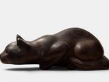 sculpture of a cat laying on its side on a white surface