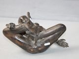 a bronze statue of a woman laying on her stomach