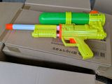 a yellow and green toy gun sitting on a cardboard box