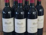 six bottles of red wine are lined up on a wooden shelf