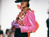 a woman that is walking down the runway wearing a pink jacket and purple pants