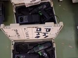 deux cartons ouverts contenant du matériel électronique, posés par terre