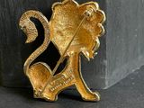 a gold brooch of a lion with a pin in it