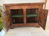 a wooden cabinet with two open doors and a plant in the corner