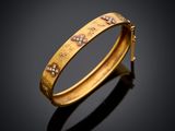 a gold bracelet with diamonds on a black background