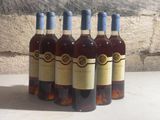 six bottles of wine are lined up in a row against a stone wall
