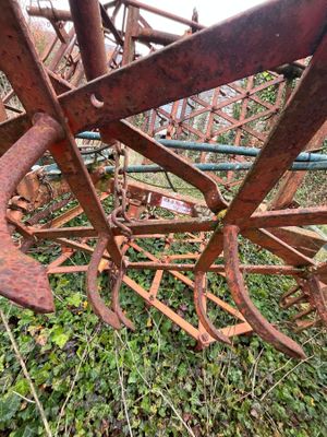 une vieille charrue rouillée posée dans l'herbe, près d'une clôture