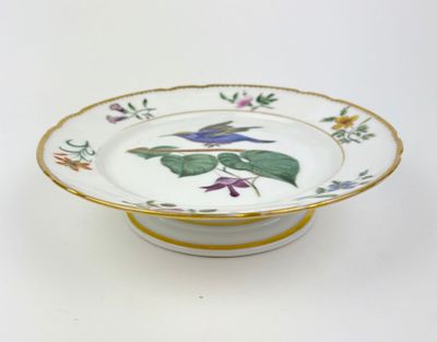 une assiette blanche avec un bord jaune et une fleur bleue