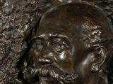 bronze bust of a man with a beard and a bow tie