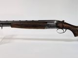 un fusil posé sur un socle transparent, devant un fond blanc
