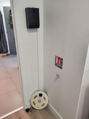 doorway view of a room with a white wall and a black speaker on the wall