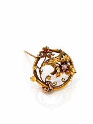 a close up of a gold broochle with flowers on it