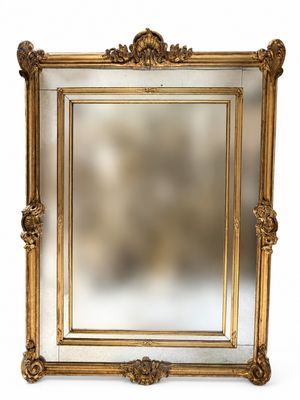 un grand miroir à cadre doré, orné de sculptures raffinées et d'un cadre décoratif