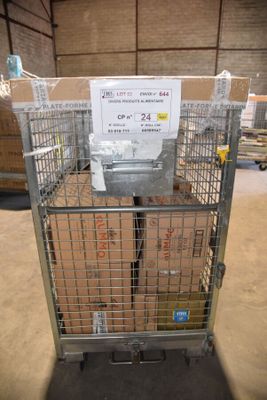 une cage métallique sur laquelle est accrochée une pancarte, dans un entrepôt