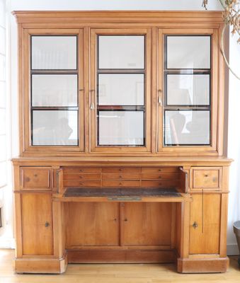 a large wooden cabinet with glass doors and a desk in front of it
