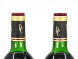 two bottles of red wine sitting next to each other on top of a table