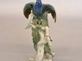 a figurine of a peacock sitting on a tree branch