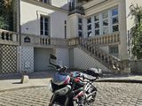 une moto garée devant une maison, dans une rue pavée