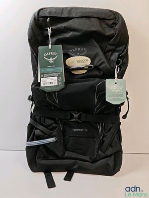 un sac à dos noir muni d'une étiquette, posé par terre