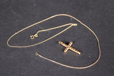 une croix en or avec une chaîne, sur un fond noir