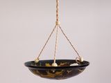 a close up of a black and gold bowl hanging from a rope