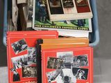 Plusieurs livres se trouvent dans un panier bleu posé sur une table
