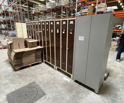 plusieurs casiers dans un entrepôt où s'entassent des cartons les uns sur les autres à même le sol